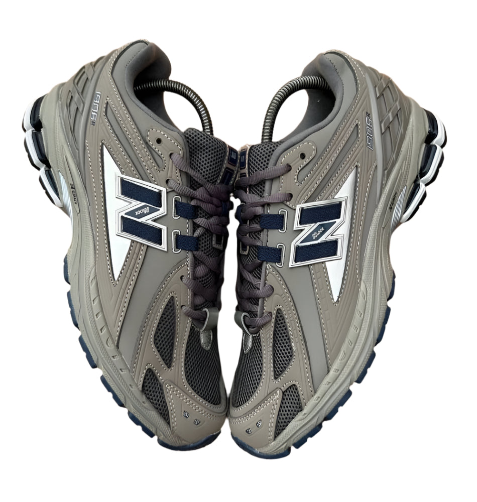 Pair of gray sneakers with a brand logo on a wooden floor.